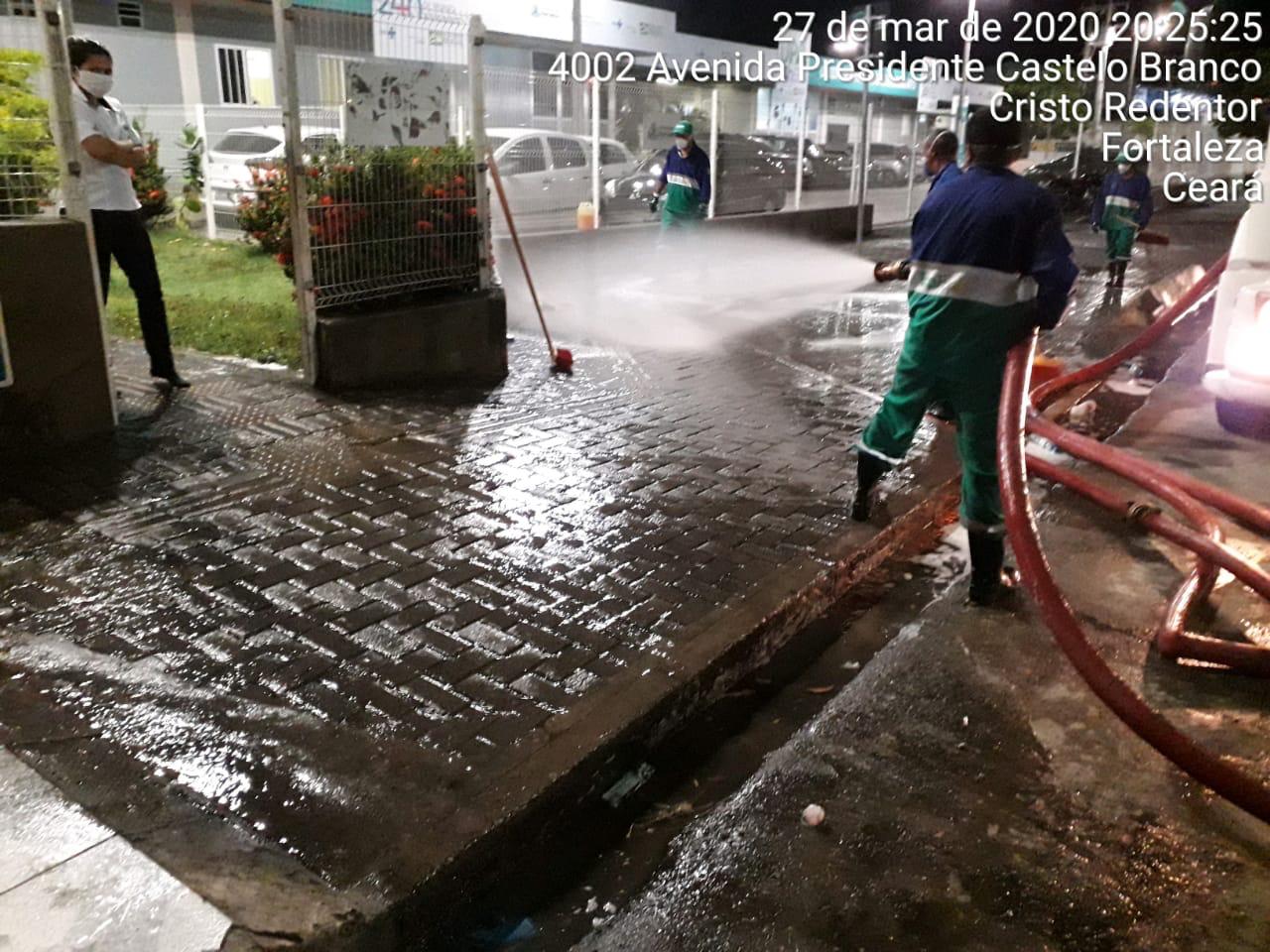 homens lavando frente de upa com mangueira jorrando água